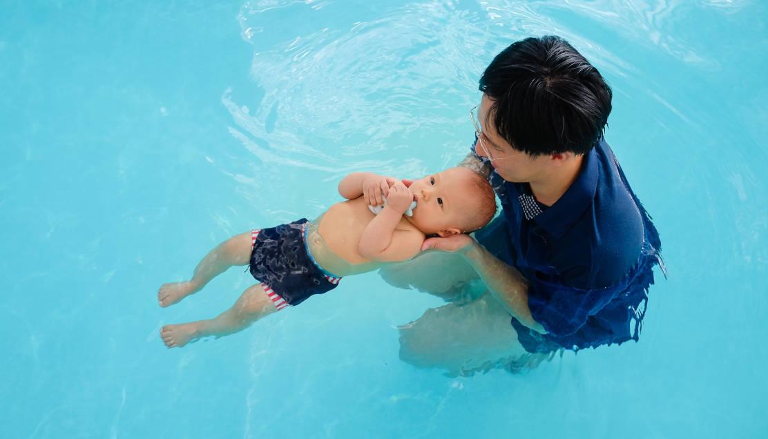 Seorang bayi sedang belajar berenang 
