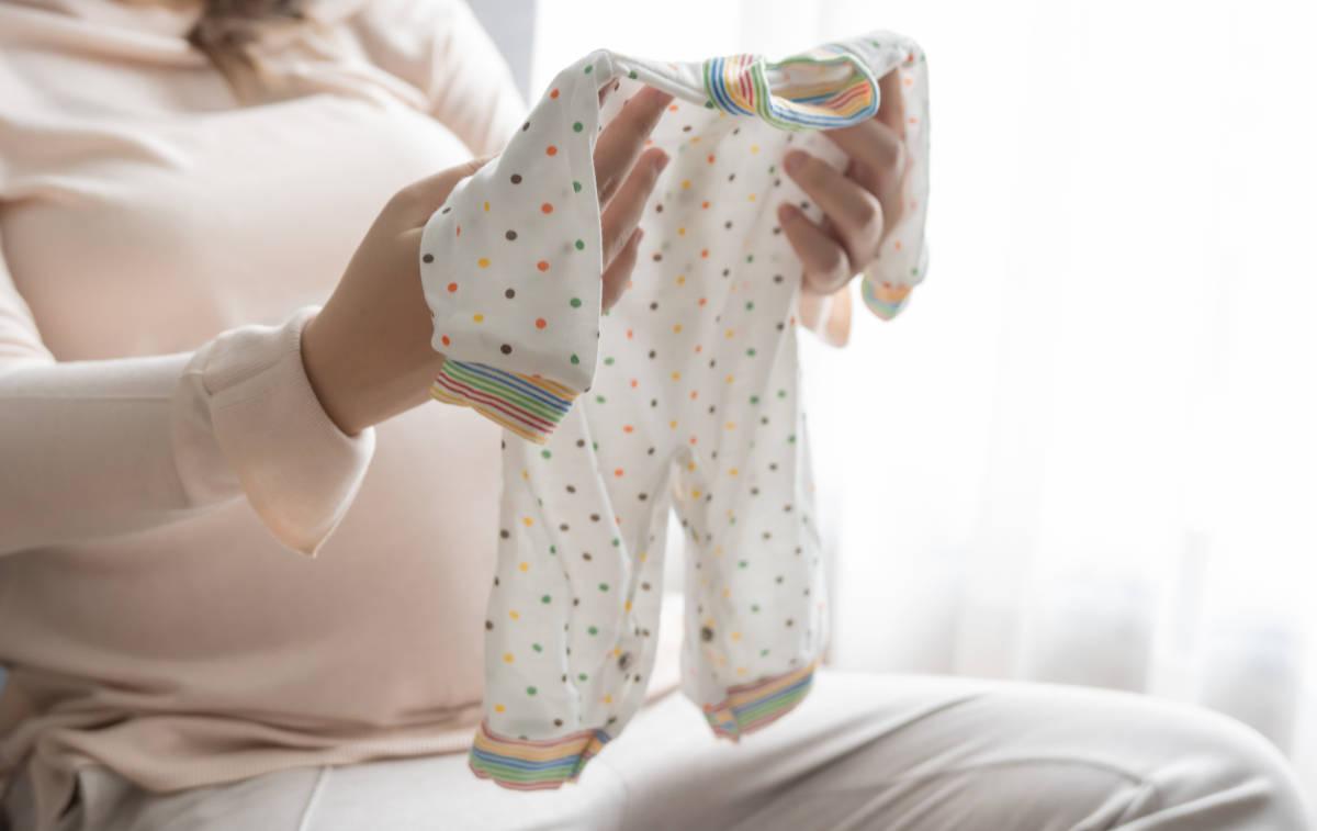 Seorang ibu sedang memegang baju bayi